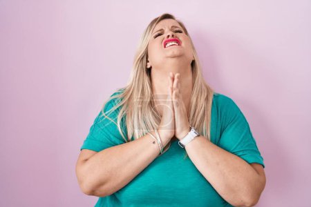 Photo for Caucasian plus size woman standing over pink background begging and praying with hands together with hope expression on face very emotional and worried. begging. - Royalty Free Image
