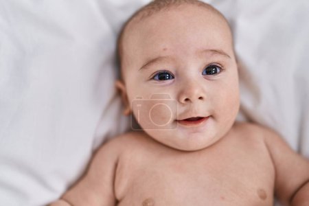 Photo for Adorable baby smiling confident lying on bed at bedroom - Royalty Free Image
