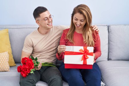 Téléchargez les photos : Homme et femme mère et fils tenant cadeau et fleurs à la maison - en image libre de droit