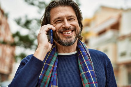 Téléchargez les photos : Moyen âge bel homme parlant au téléphone à la ville - en image libre de droit