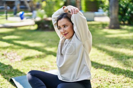 Téléchargez les photos : Middle age woman smiling confident stretching at park - en image libre de droit