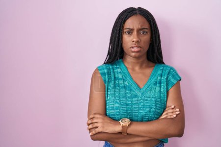 Téléchargez les photos : Young african american with braids standing over pink background skeptic and nervous, disapproving expression on face with crossed arms. negative person. - en image libre de droit