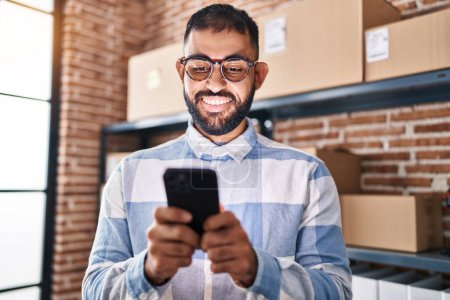 Téléchargez les photos : Jeune homme hispanique ecommerce travailleur d'affaires en utilisant smartphone au bureau - en image libre de droit