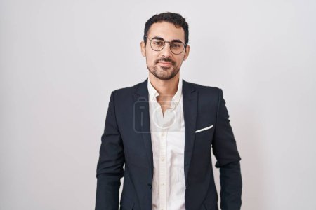 Foto de Handsome business hispanic man standing over white background relaxed with serious expression on face. simple and natural looking at the camera. - Imagen libre de derechos