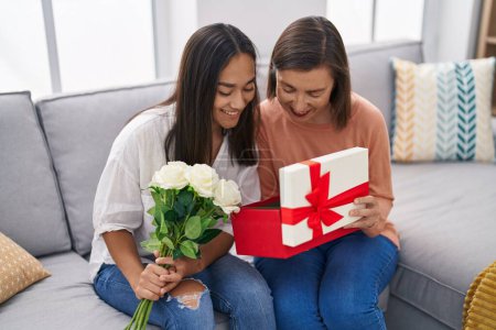 Foto de Dos mujeres madre e hija sosteniendo flores desembalaje regalo en casa - Imagen libre de derechos