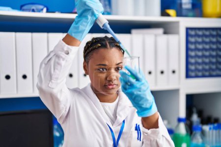 Photo for African american woman scientist pouring liquid on test tube at laboratory - Royalty Free Image