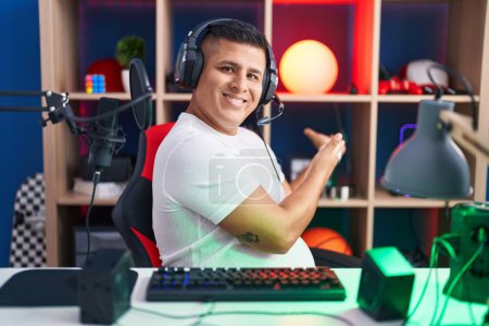 Téléchargez les photos : Jeune homme hispanique jouant à des jeux vidéo invitant à entrer souriant naturel avec la main ouverte - en image libre de droit