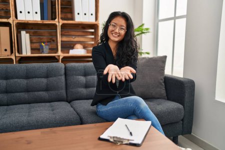 Photo for Young asian woman at consultation office smiling with hands palms together receiving or giving gesture. hold and protection - Royalty Free Image