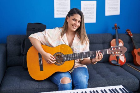 Téléchargez les photos : Jeune musicienne hispanique jouant de la guitare classique au studio de musique - en image libre de droit
