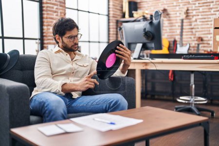 Photo for Young hispanic man musician holding vinyl disc at music studio - Royalty Free Image