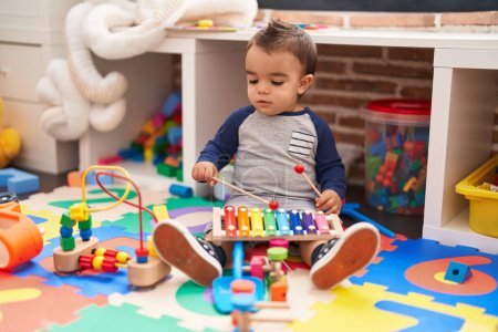 Photo for Adorable hispanic toddler playing xylophone sitting on floor at kindergarten - Royalty Free Image