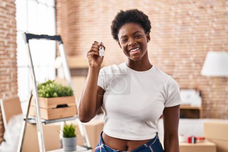 Photo for African american woman holding keys of new home looking positive and happy standing and smiling with a confident smile showing teeth - Royalty Free Image