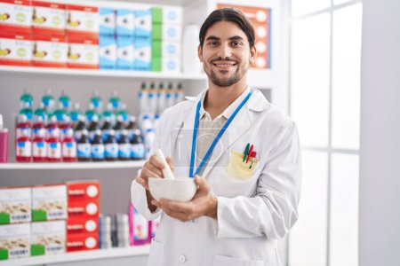 Téléchargez les photos : Young hispanic man pharmacist smiling confident working at pharmacy - en image libre de droit