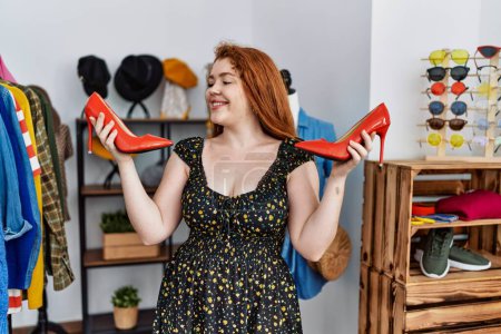 Téléchargez les photos : Jeune rousse femme chaussures à talons hauts shopping au magasin de vêtements - en image libre de droit