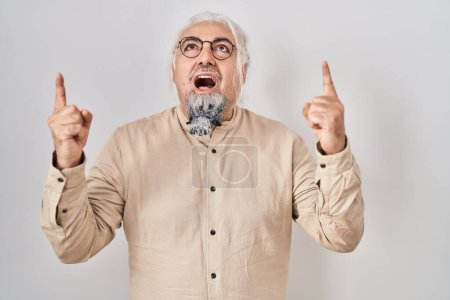 Photo for Middle age man with grey hair standing over isolated background amazed and surprised looking up and pointing with fingers and raised arms. - Royalty Free Image