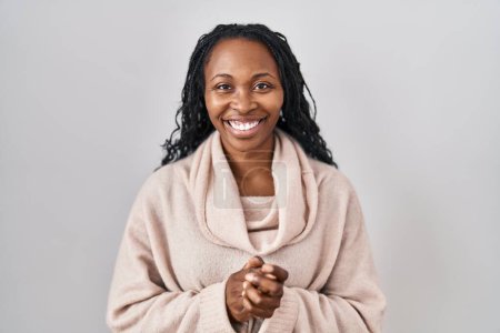 Téléchargez les photos : Femme africaine debout sur fond blanc avec les mains jointes et les doigts croisés souriant détendu et joyeux. succès et optimisme - en image libre de droit