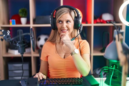 Photo for Young woman playing video games thinking worried about a question, concerned and nervous with hand on chin - Royalty Free Image