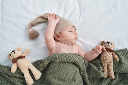 Foto de Adorable caucasian baby lying on bed with relaxed expression at bedroom - Imagen libre de derechos