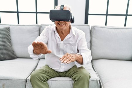 Foto de Hombre mayor jugando videojuego con gafas de realidad virtual en casa - Imagen libre de derechos