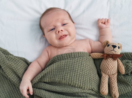 Photo for Adorable caucasian baby lying on bed with relaxed expression at bedroom - Royalty Free Image