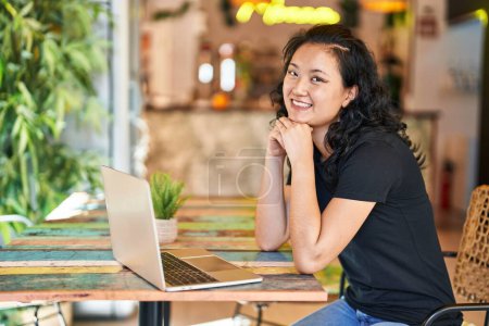 Foto de Joven mujer china usando portátil sentado en la mesa en el restaurante - Imagen libre de derechos