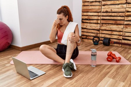 Photo for Young redhead woman watching training tutorial at the gym tired rubbing nose and eyes feeling fatigue and headache. stress and frustration concept. - Royalty Free Image