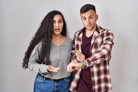 Téléchargez les photos : Young hispanic couple standing over white background in hurry pointing to watch time, impatience, upset and angry for deadline delay - en image libre de droit