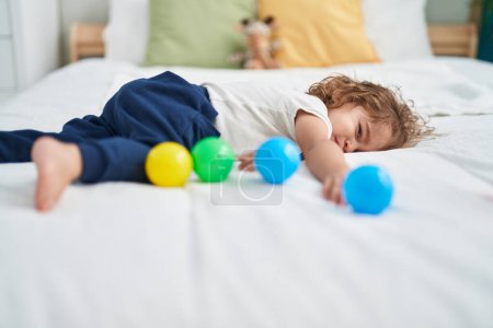 Foto de Adorable niño hispano acostado en la cama llorando en el dormitorio - Imagen libre de derechos