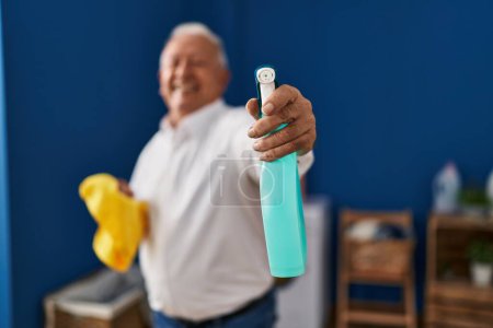 Photo for Senior man smiling confident holding cleaning products at laundry room - Royalty Free Image
