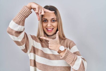 Téléchargez les photos : Young blonde woman wearing turtleneck sweater over isolated background smiling making frame with hands and fingers with happy face. creativity and photography concept. - en image libre de droit