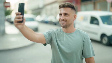 Téléchargez les photos : Young hispanic man smiling confident making selfie by the smartphone at street - en image libre de droit
