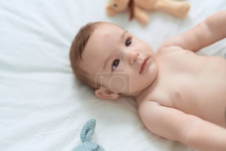 Photo for Adorable toddler lying on bed with teddy bear at bedroom - Royalty Free Image