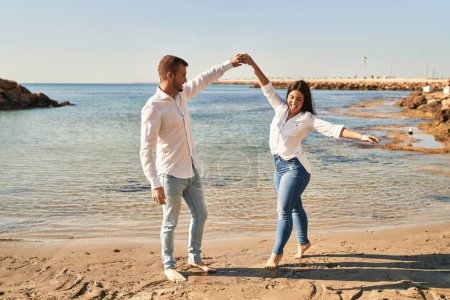 Foto de Hombre y mujer pareja sonriendo feliz bailando en la playa - Imagen libre de derechos