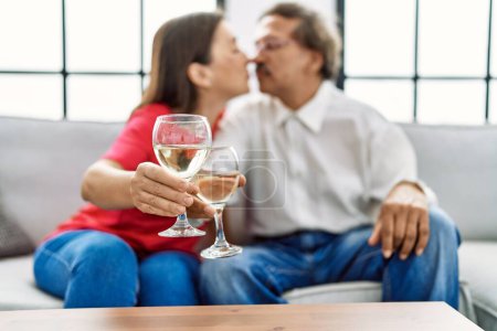 Foto de Hombre y mujer de mediana edad pareja besando y brindando con champán en casa - Imagen libre de derechos