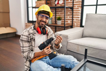 Photo for Young hispanic man worker smiling confident holding drill at home - Royalty Free Image
