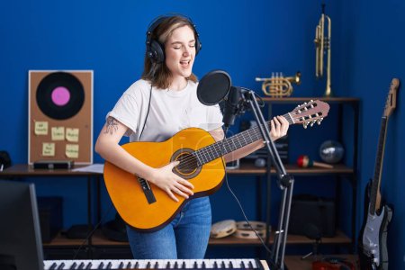 Photo for Young woman musician singing song playing classical guitar at music studio - Royalty Free Image