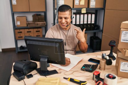 Téléchargez les photos : Jeune homme hispanique travaillant dans une petite entreprise commerce électronique souriant heureux pointant avec la main et le doigt - en image libre de droit