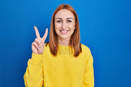 Photo for Young woman standing over blue background showing and pointing up with fingers number two while smiling confident and happy. - Royalty Free Image