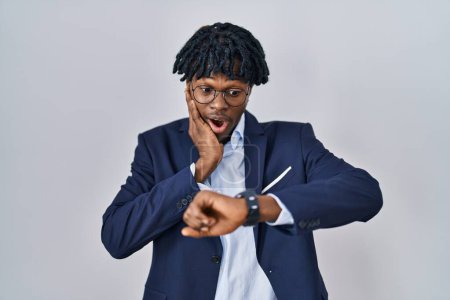 Téléchargez les photos : Young african man with dreadlocks wearing business jacket over white background looking at the watch time worried, afraid of getting late - en image libre de droit