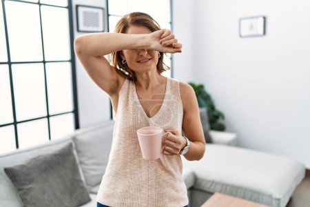 Photo for Middle age woman drinking a cup coffee at home smiling cheerful playing peek a boo with hands showing face. surprised and exited - Royalty Free Image