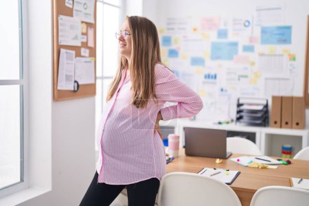 Foto de Young pregnant woman business worker suffering for backache at office - Imagen libre de derechos