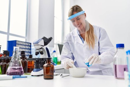 Foto de Mujer rubia joven vistiendo uniforme científico trabajando en el laboratorio - Imagen libre de derechos