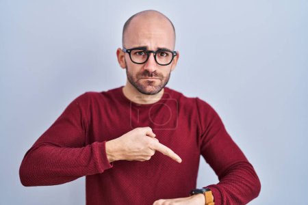 Photo for Young bald man with beard standing over white background wearing glasses in hurry pointing to watch time, impatience, upset and angry for deadline delay - Royalty Free Image