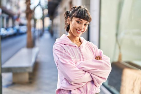 Téléchargez les photos : Jeune femme souriante confiante debout avec les bras croisés geste à la rue - en image libre de droit