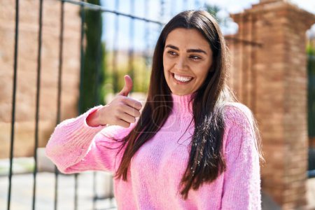Téléchargez les photos : Young hispanic woman smiling confident doing ok sign with thumb up at street - en image libre de droit