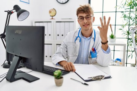 Photo for Young caucasian doctor man working at the clinic showing and pointing up with fingers number three while smiling confident and happy. - Royalty Free Image