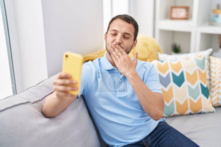 Photo for Young man having video call sitting on sofa at home - Royalty Free Image