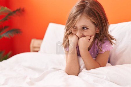 Téléchargez les photos : Adorable fille hispanique souriant confiant assis sur le lit dans la chambre - en image libre de droit