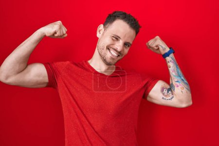 Photo for Young hispanic man standing over red background showing arms muscles smiling proud. fitness concept. - Royalty Free Image