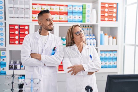 Téléchargez les photos : Pharmacien homme et femme debout avec les bras croisés geste à la pharmacie - en image libre de droit
